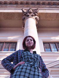 Low angle portrait of woman standing against building