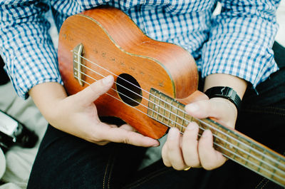 Midsection of man playing guitar