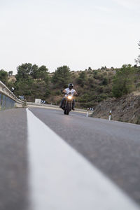 Man riding motorcycle on road against sky