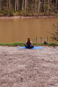 Woman sitting on land by lake