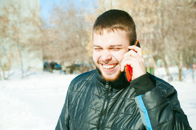 Smiling man in warm clothing talking on mobile phone