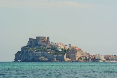 Sea by buildings against clear sky