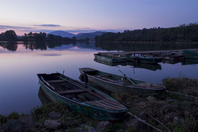 Boats moored in calm lake against sky