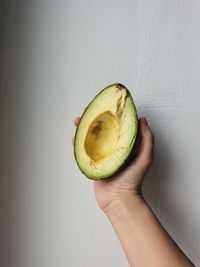 Cropped image of hand holding apple against wall