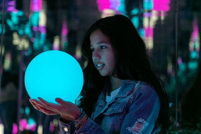 Young teen girl holding a blue light in shape of a ball