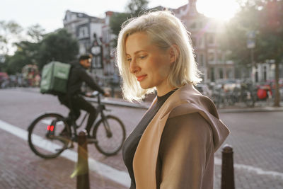 Young woman with bicycle on street in city