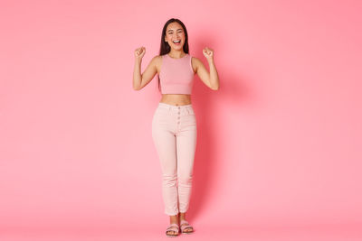 Portrait of woman standing against pink background