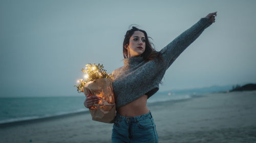 Happy young girl enjoys life on the beach with colorful lights on bag