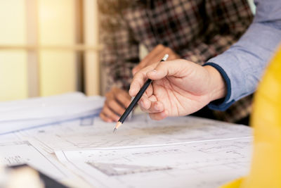 Cropped image of architects working over blueprint at office