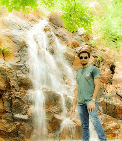 Portrait of boy standing against waterfall