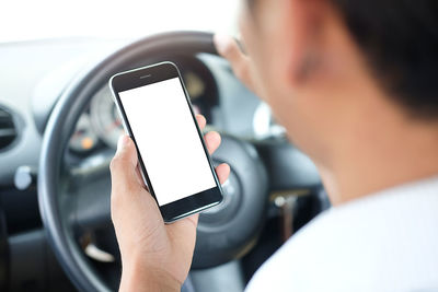 Cropped image of man using smart phone in car
