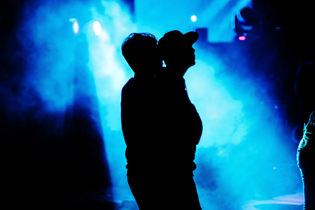 SILHOUETTE PEOPLE STANDING AT ILLUMINATED NIGHTCLUB