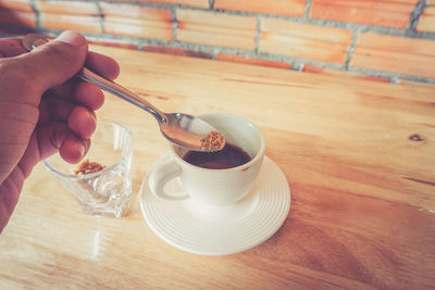 Close-up of cropped hand mixing brown sugar in hot chocolate table