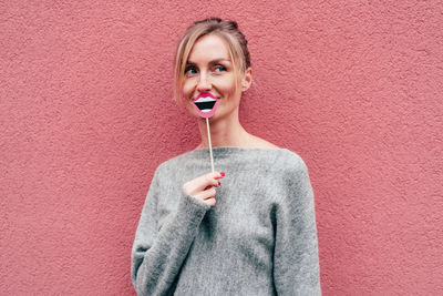 Portrait of a smiling young woman against wall