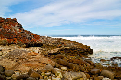 Rock formation on beach against sky