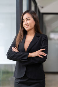 Portrait of young woman standing against wall