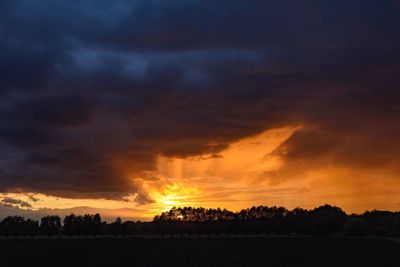 Silhouette landscape against dramatic sky during sunset