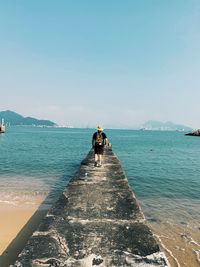 Rear view of people on sea against sky