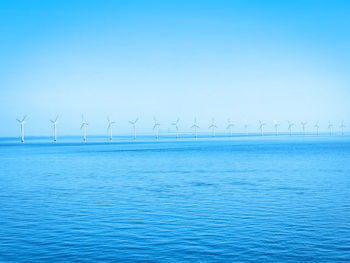 Wind turbines in sea against sky