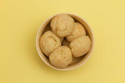 High angle view of cookies in bowl against yellow background