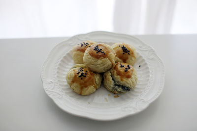 There are some delicious black sesame egg yolk pastries freshly baked on the plate on the table