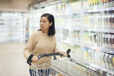 Woman in supermarket standing in front of fridge