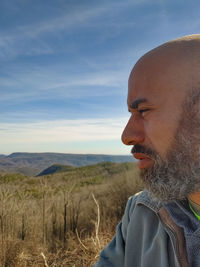 Portrait of man looking at camera on field against sky
