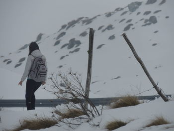 Rear view of woman on snow covered field against sky