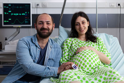 Portrait of man with pregnant wife at hospital