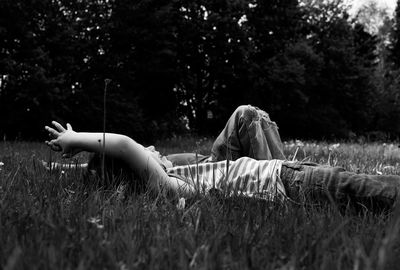 Siblings lying down on field against trees