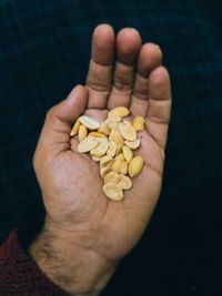 Cropped hand holding peanuts against black background