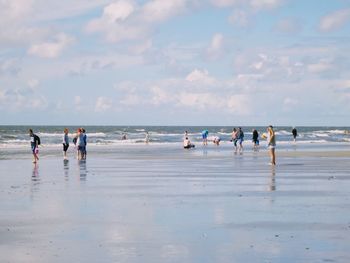 People walking on beach against sky