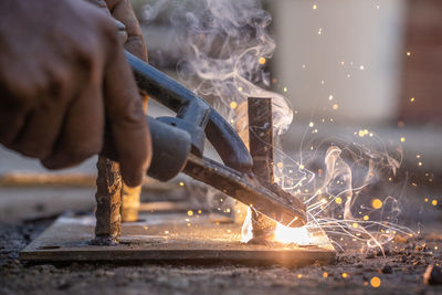 Cropped hands of worker welding metal in workshop