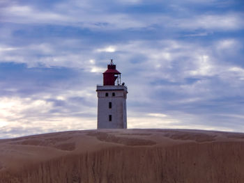 Lighthouse on street amidst buildings against sky