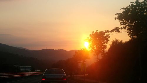 Cars on road against sky during sunset
