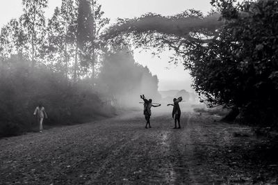 People standing on dirt road in foggy weather