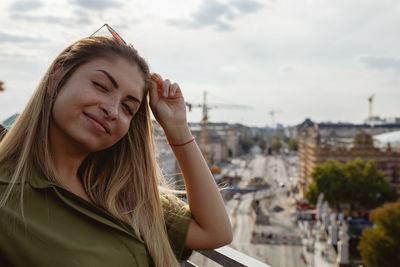 Beautiful young woman in city against sky