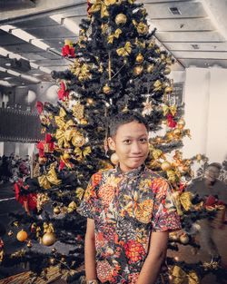 Portrait of young woman standing by tree