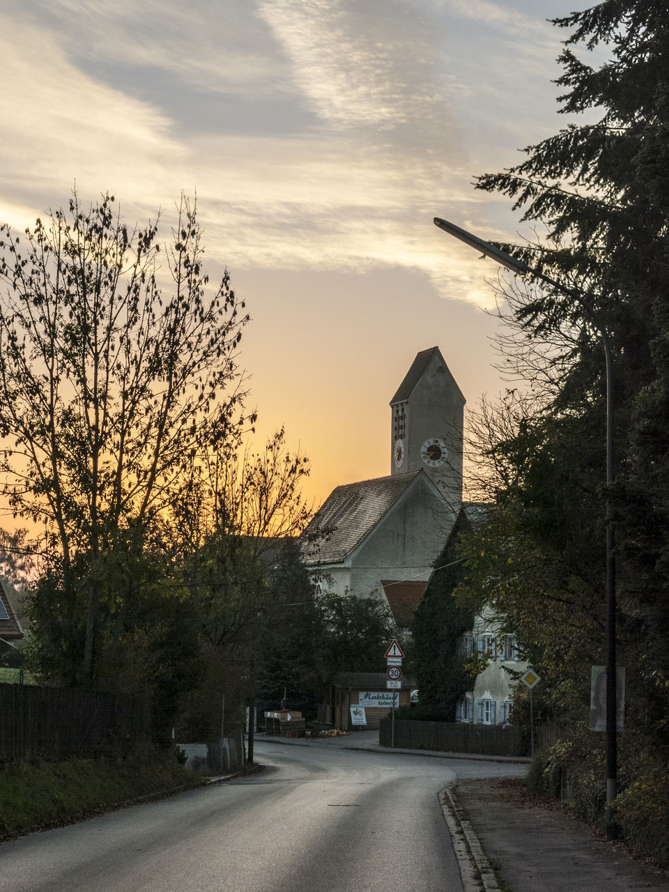 ROAD AMIDST BUILDINGS AGAINST SKY AT SUNSET