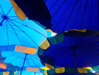 Low angle view of multi colored umbrellas hanging against blue sky