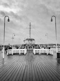 Sailboats on pier by sea against sky