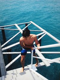 High angle view of shirtless man on built structure in sea