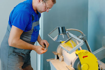 The turner sharpens the part on a grinding machine in the workshop. an adult man of 