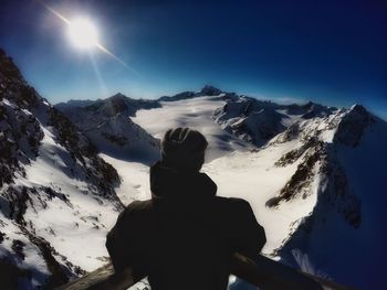 Rear view of man standing at observation point against snowcapped mountains