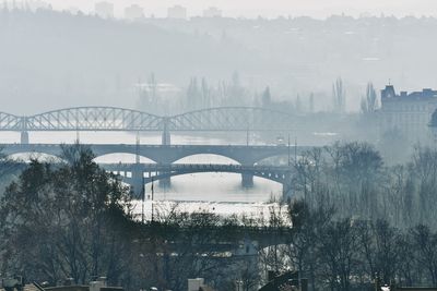 Bridge over river in city against sky