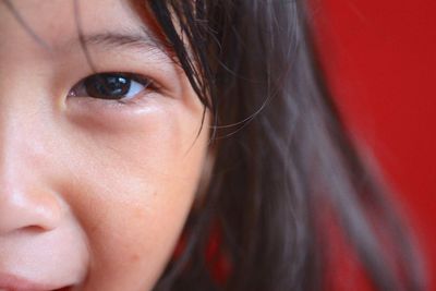 Cropped portrait of girl against red background