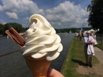 Midsection of woman holding ice cream cone against sky