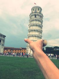 Optical illusion of cropped hand holding leaning tower of pisa