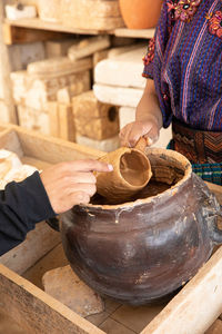 Close up of a female hand holding a hand made ceramic mug while a male hand touches it