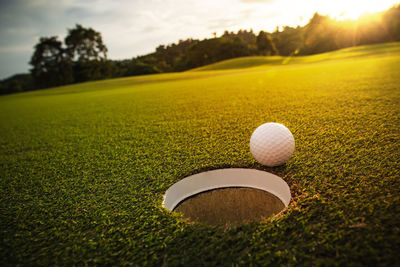 Close-up of golf ball on field against sky during sunset